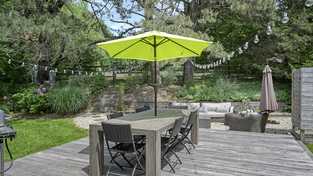 An outdoor patio with a dining table beneath a bright green umbrella.