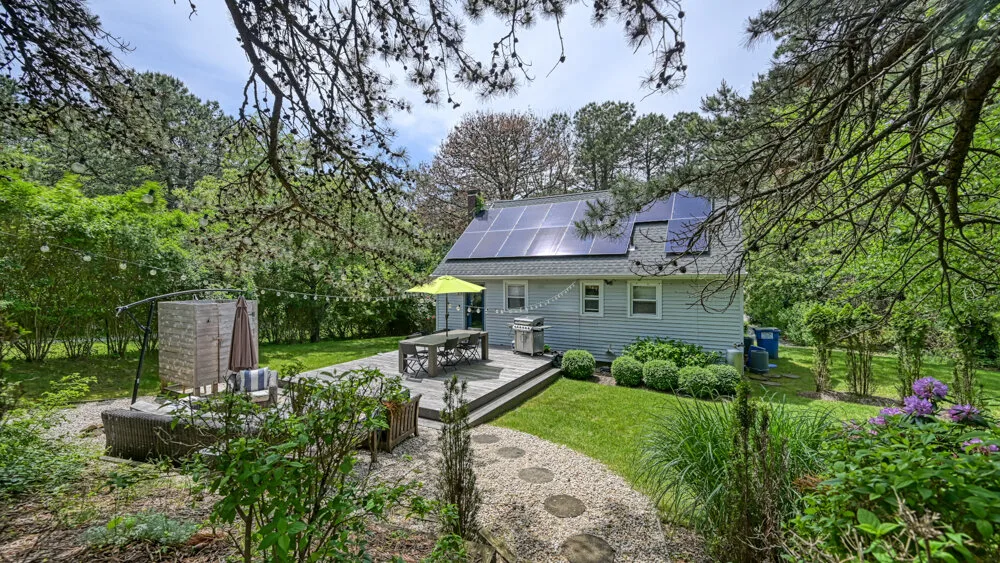 A garden patio with a stone path, outdoor seating, and a house in the background.