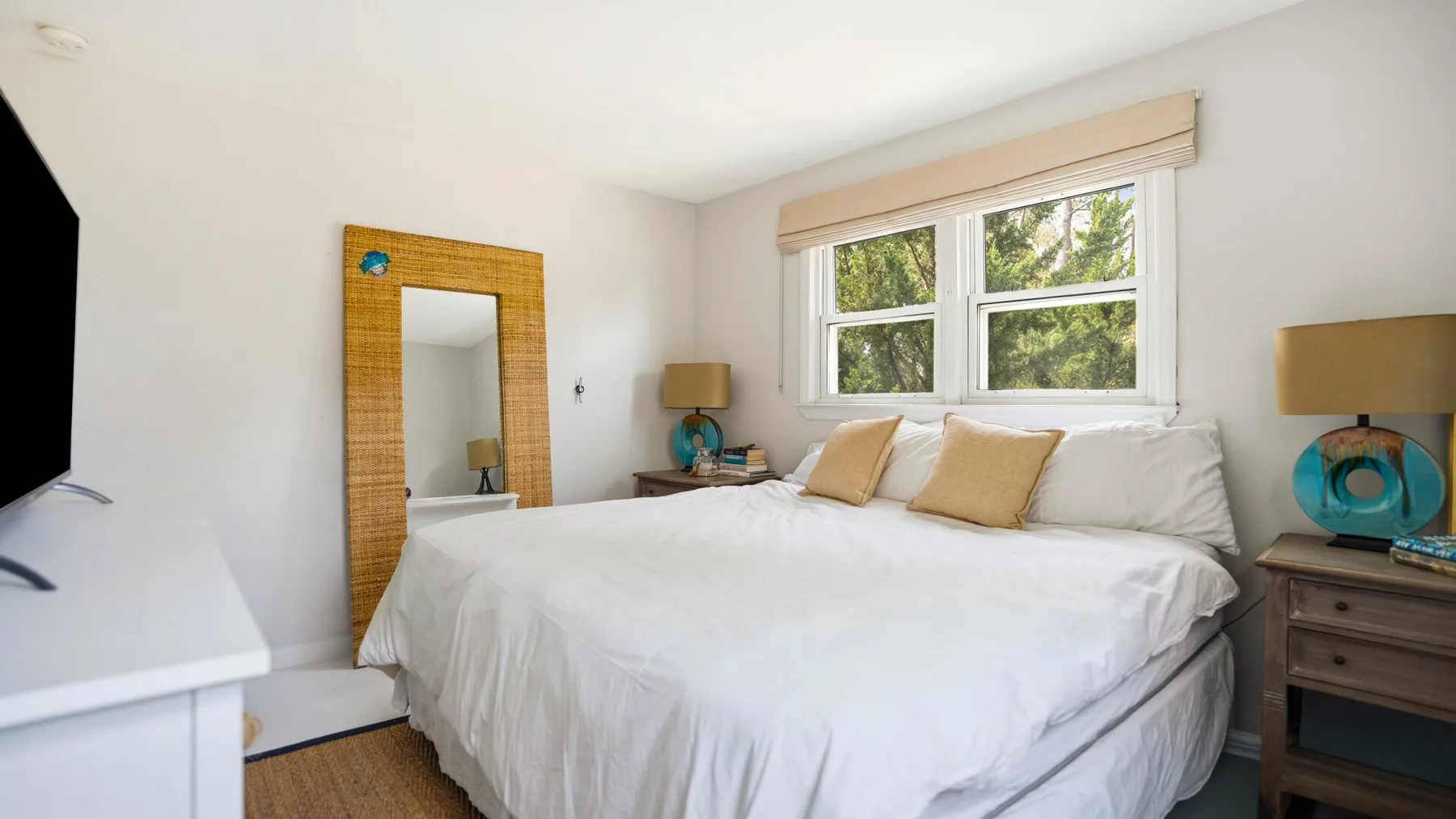 Un dormitorio luminoso con una cama grande, una ventana y mesitas de noche.