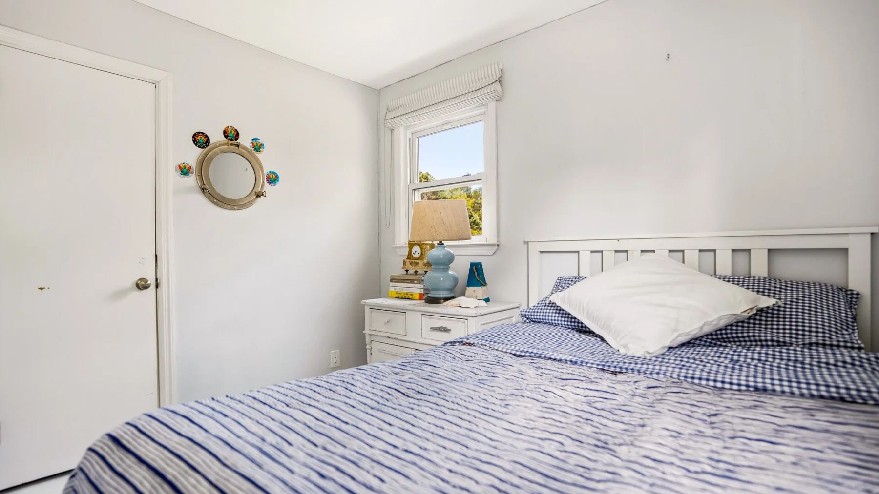 Un dormitorio con una cama, una mesita de noche y una ventana.