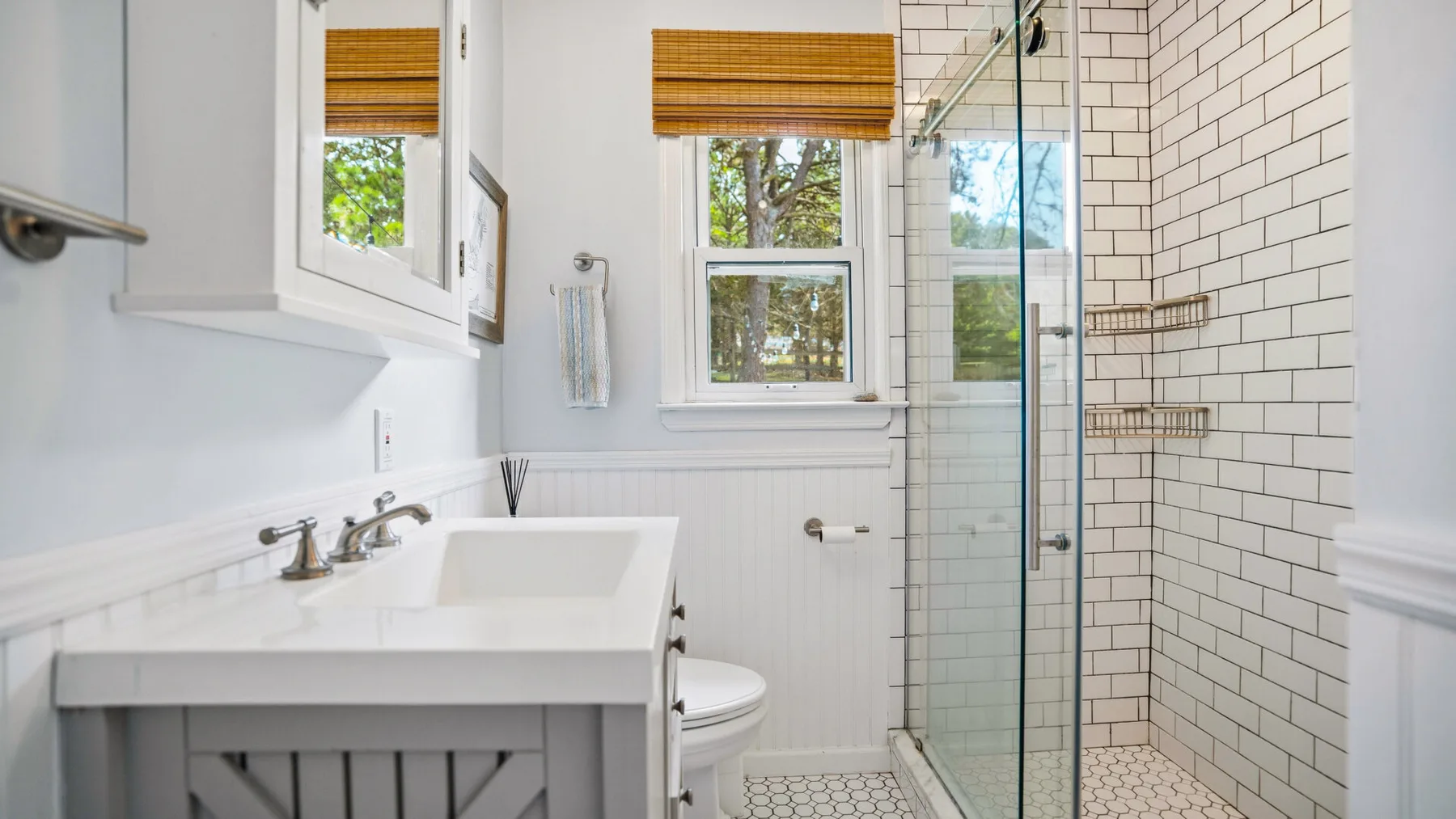Un baño luminoso con lavabo, inodoro y ducha de vidrio.