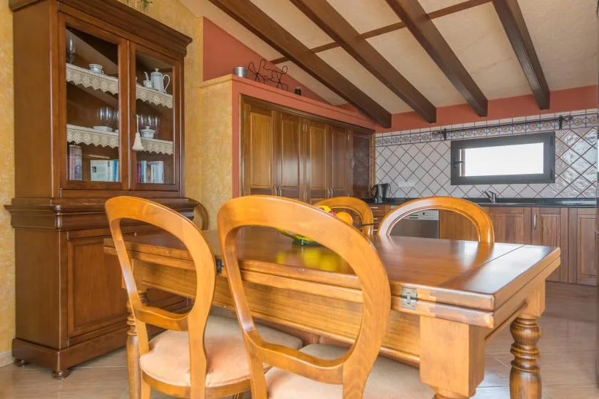 A dining area with a wooden table and chairs beside a display cabinet.