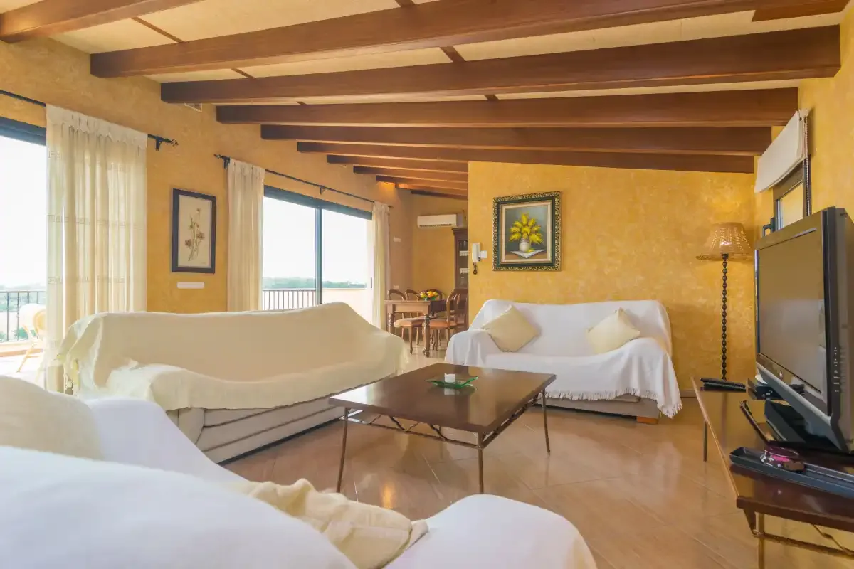 A bright living room with seating, a coffee table, and large windows.