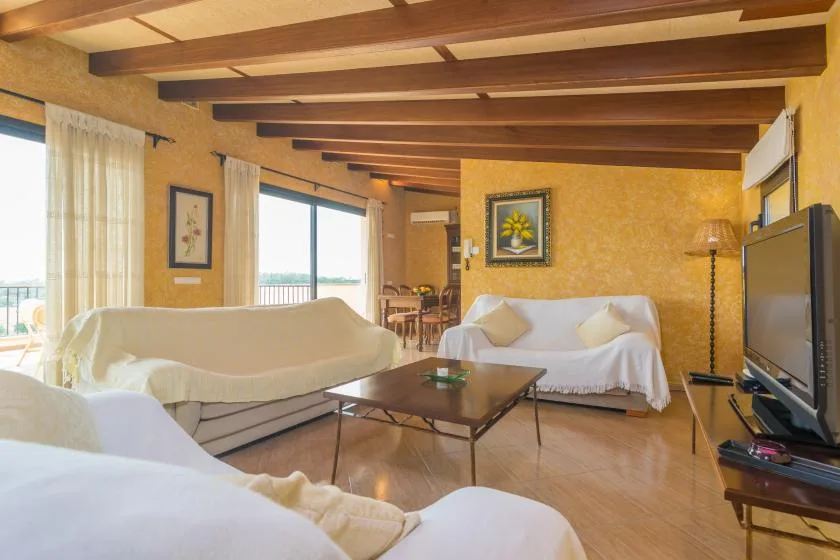 Sala de estar con asientos, una mesa de centro y ventanales.