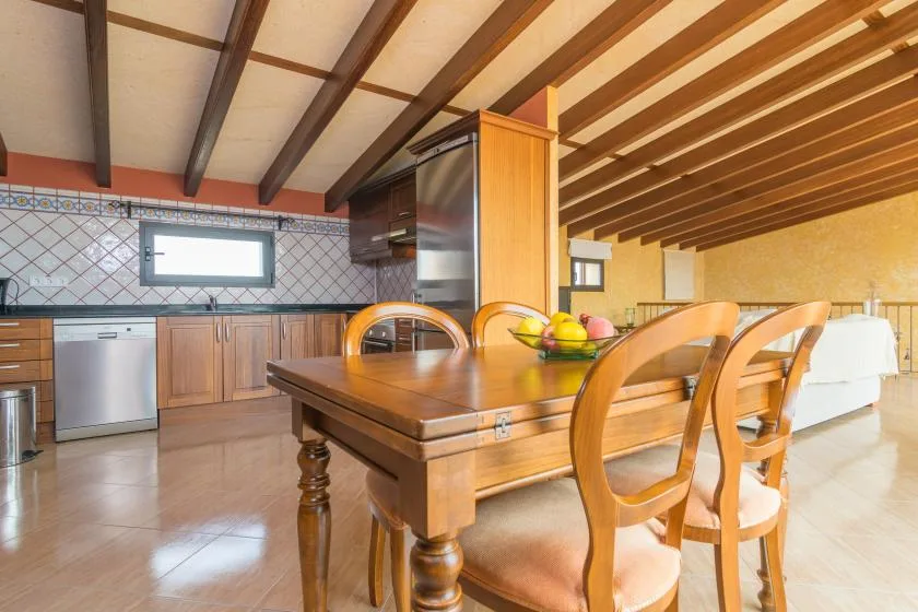 A dining area with a wooden table and chairs beside the kitchen.