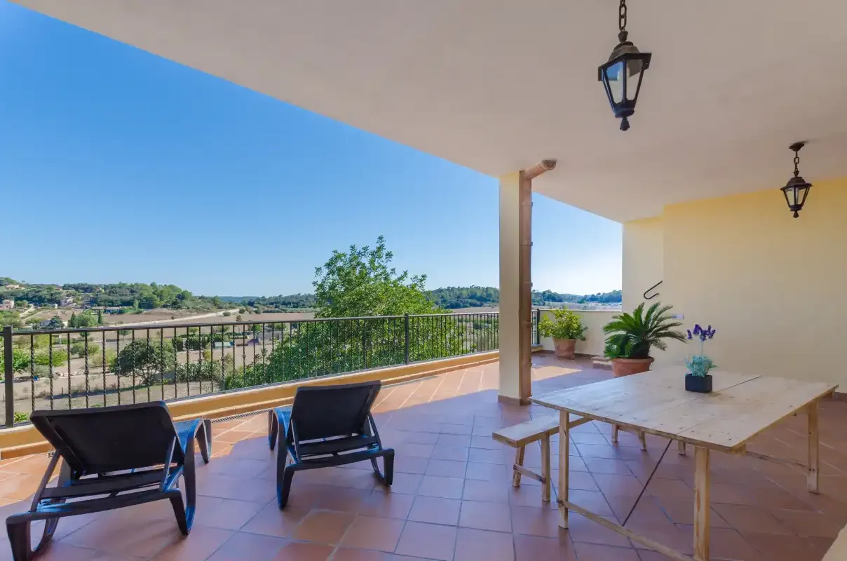 A covered outdoor terrace overlooks the surrounding countryside, with seating and a table.