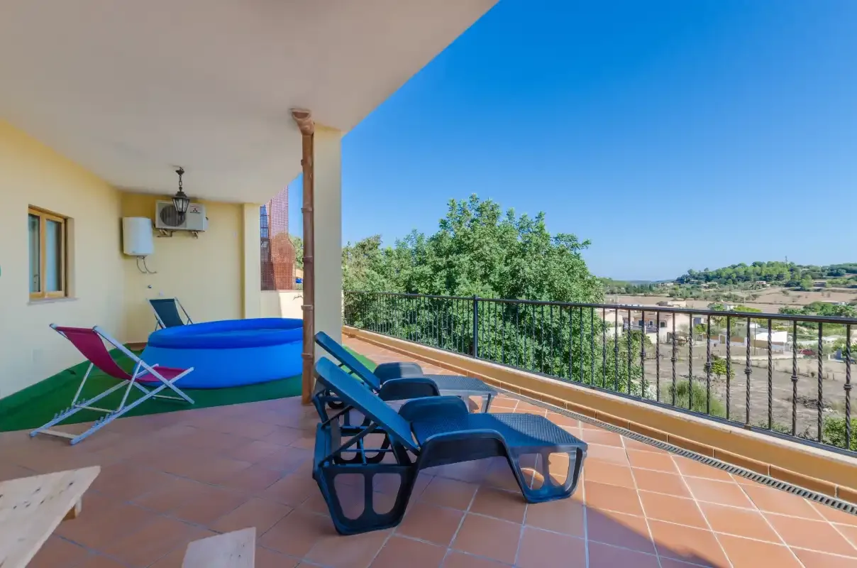 A covered terrace with lounge seating, a table, and open countryside views.
