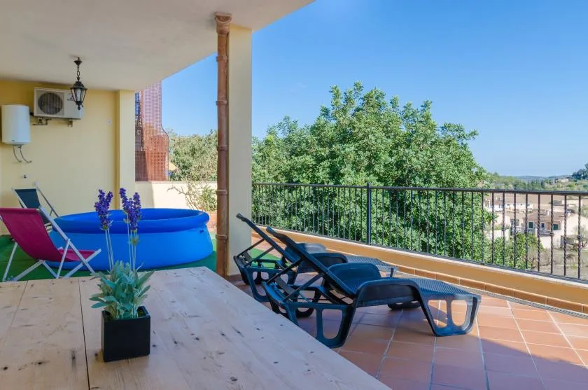An outdoor terrace with lounge seating, a small pool, and views of trees.