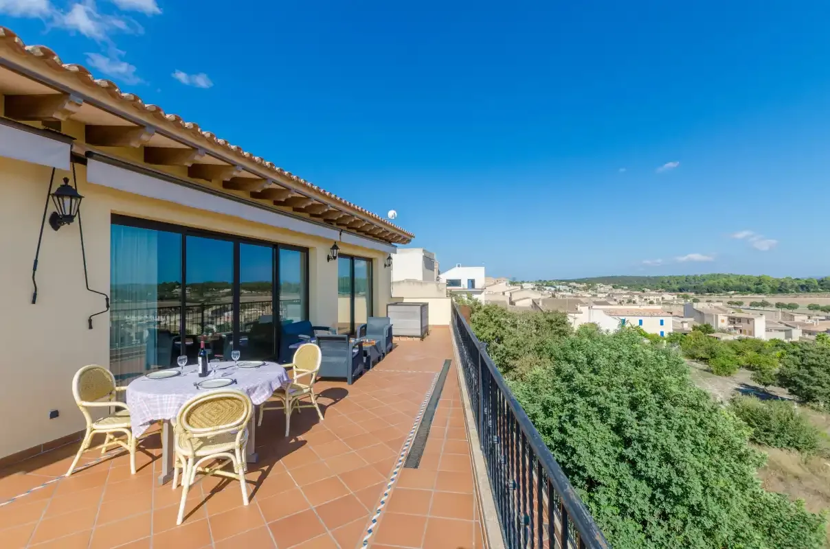 A tiled outdoor terrace with seating overlooks a green landscape.