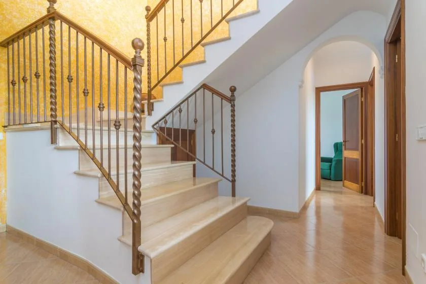 A tiled hallway with a broad staircase and an open doorway.