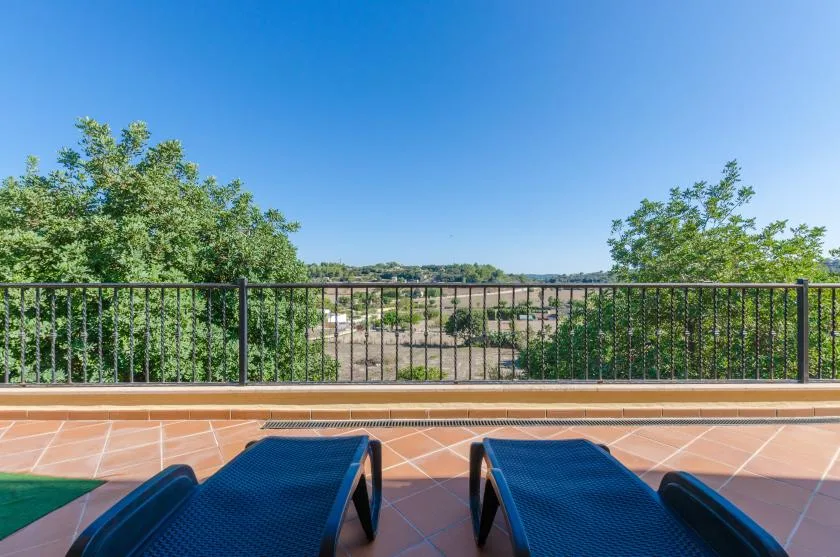 Outdoor terrace with two lounge chairs facing a tree-lined landscape.