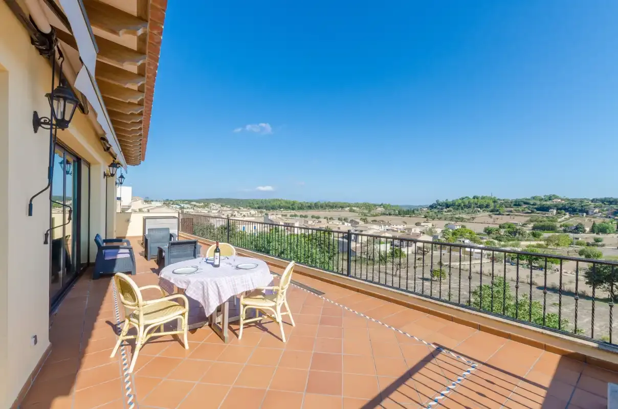A tiled terrace has outdoor seating beside a railing overlooking the surrounding landscape.