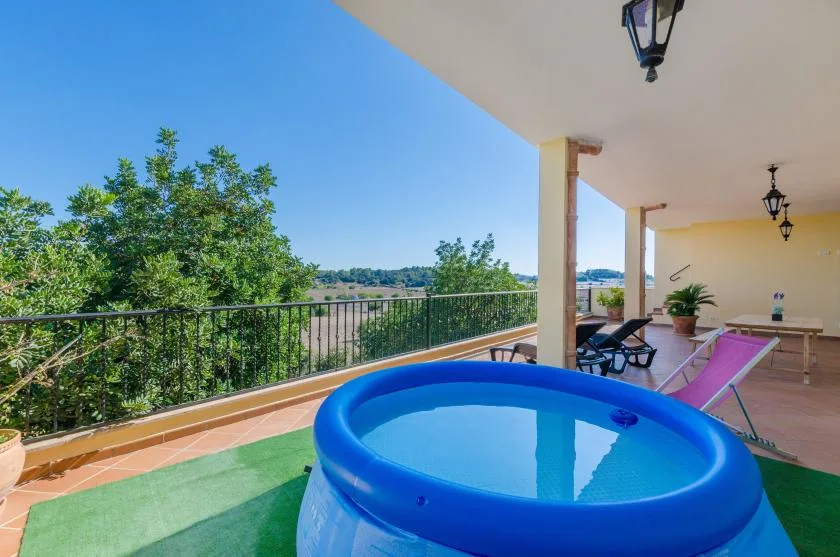 A covered outdoor terrace overlooks greenery, with a blue inflatable pool in the foreground.