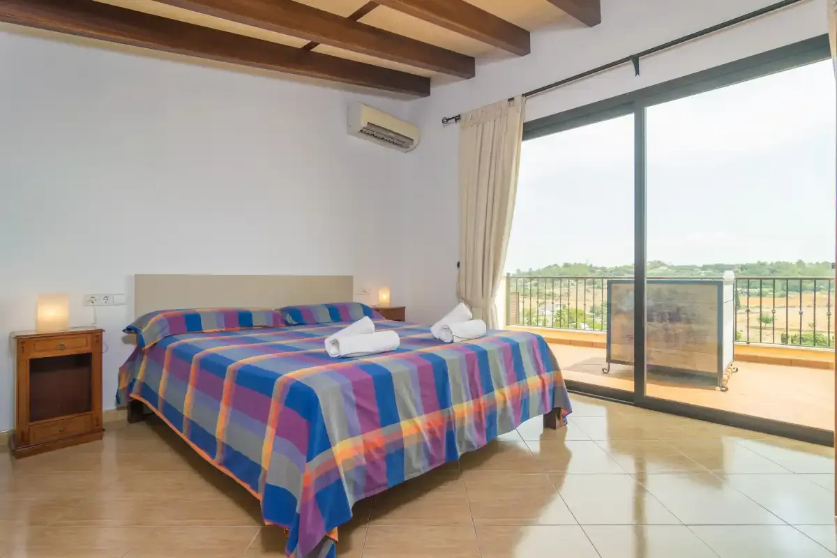 A bedroom with a colorful bedspread and sliding glass doors opening onto a balcony.