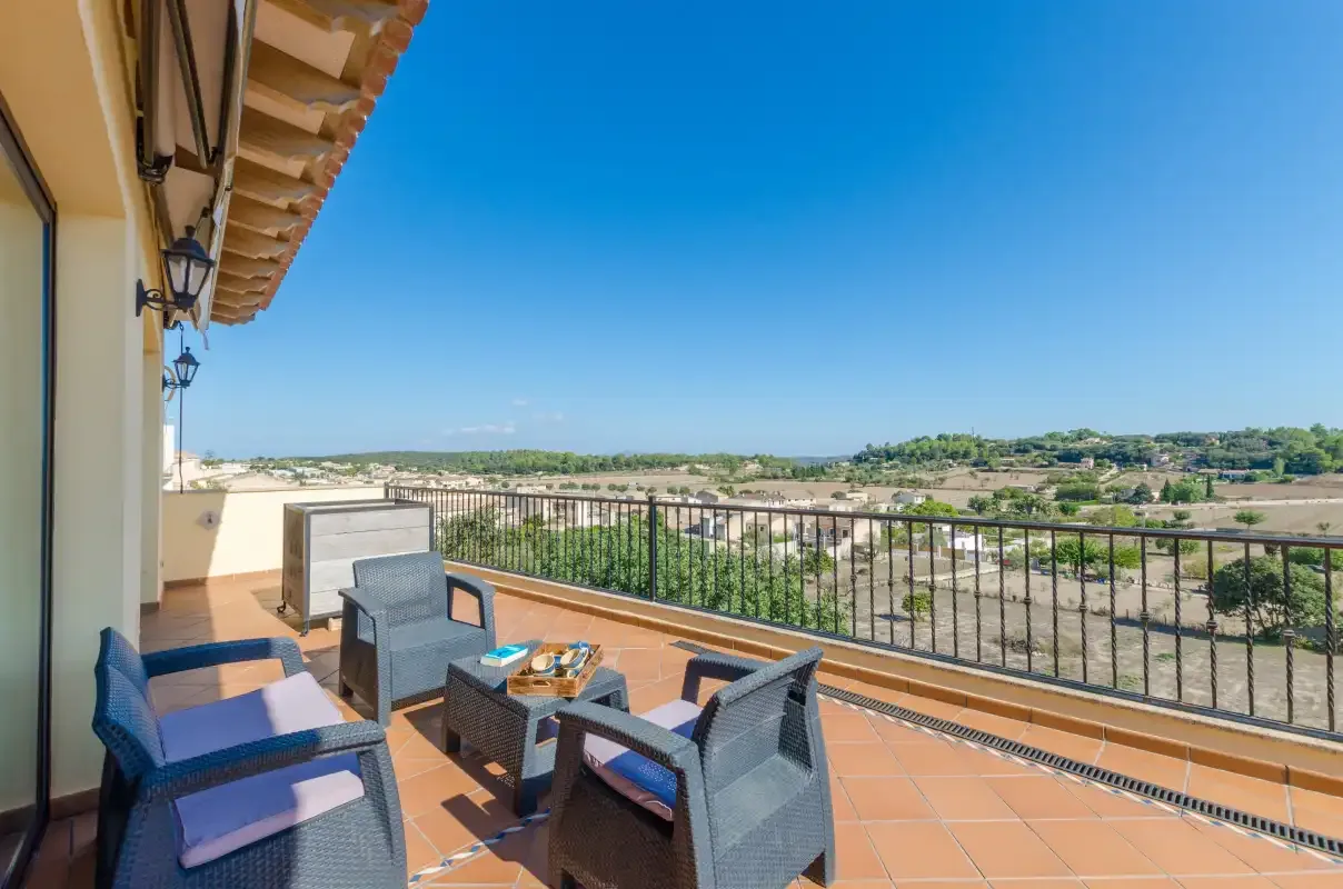 A sunny terrace with outdoor seating overlooks a rural landscape.