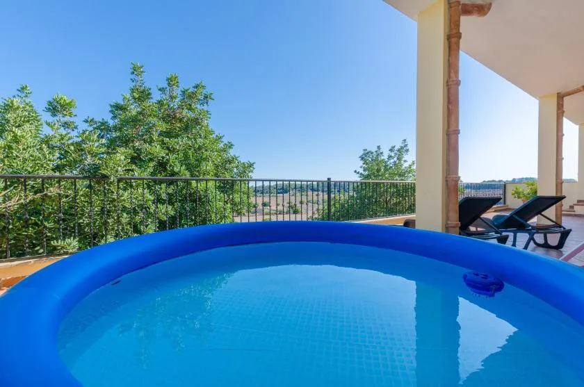 A blue outdoor pool sits beside a covered terrace with lounge seating.