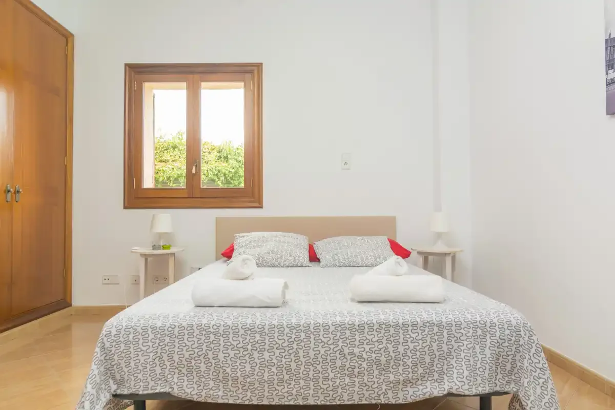 A bedroom with a bed beneath a wooden-framed window.