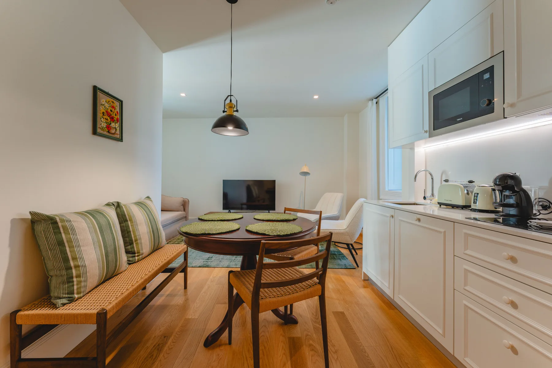 Una sala-comedor de planta abierta con una cocina compacta junto a la pared.