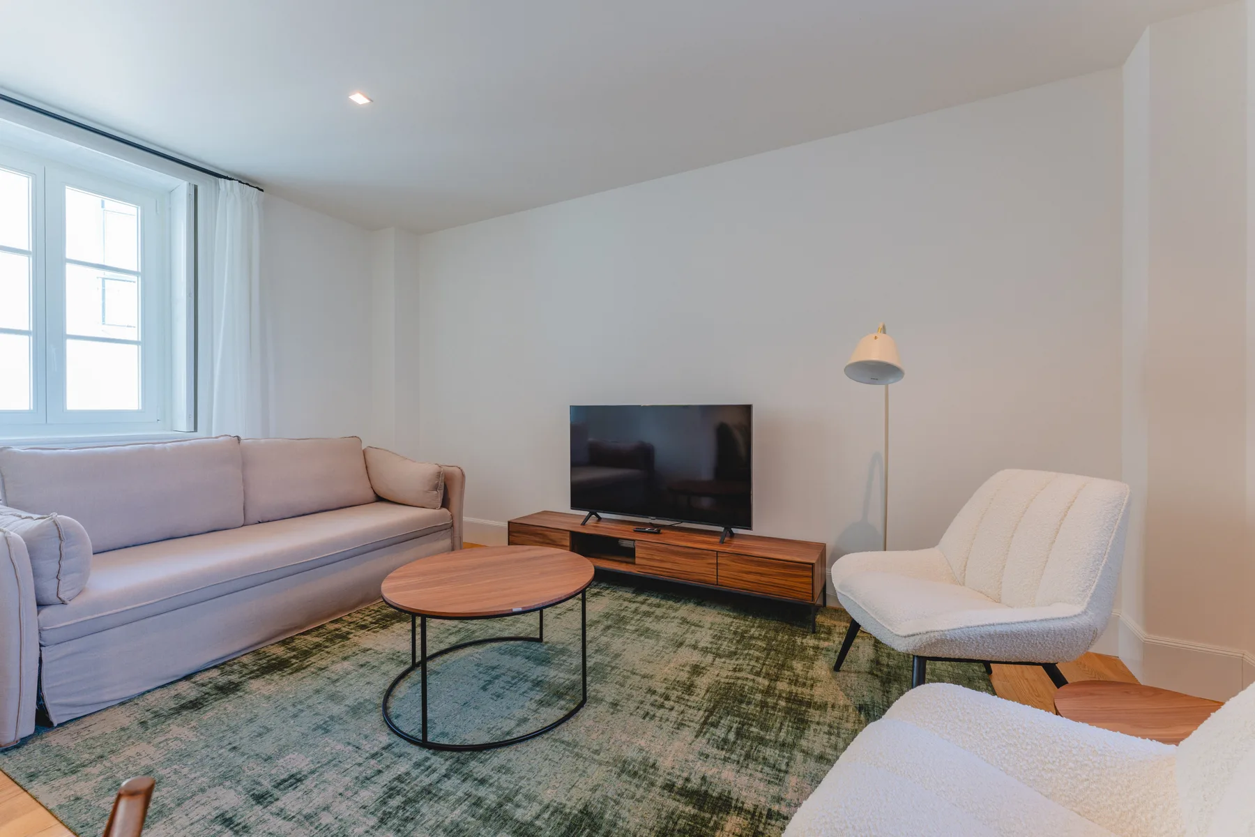 Una sala de estar luminosa con asientos, un televisor y una mesa de centro.