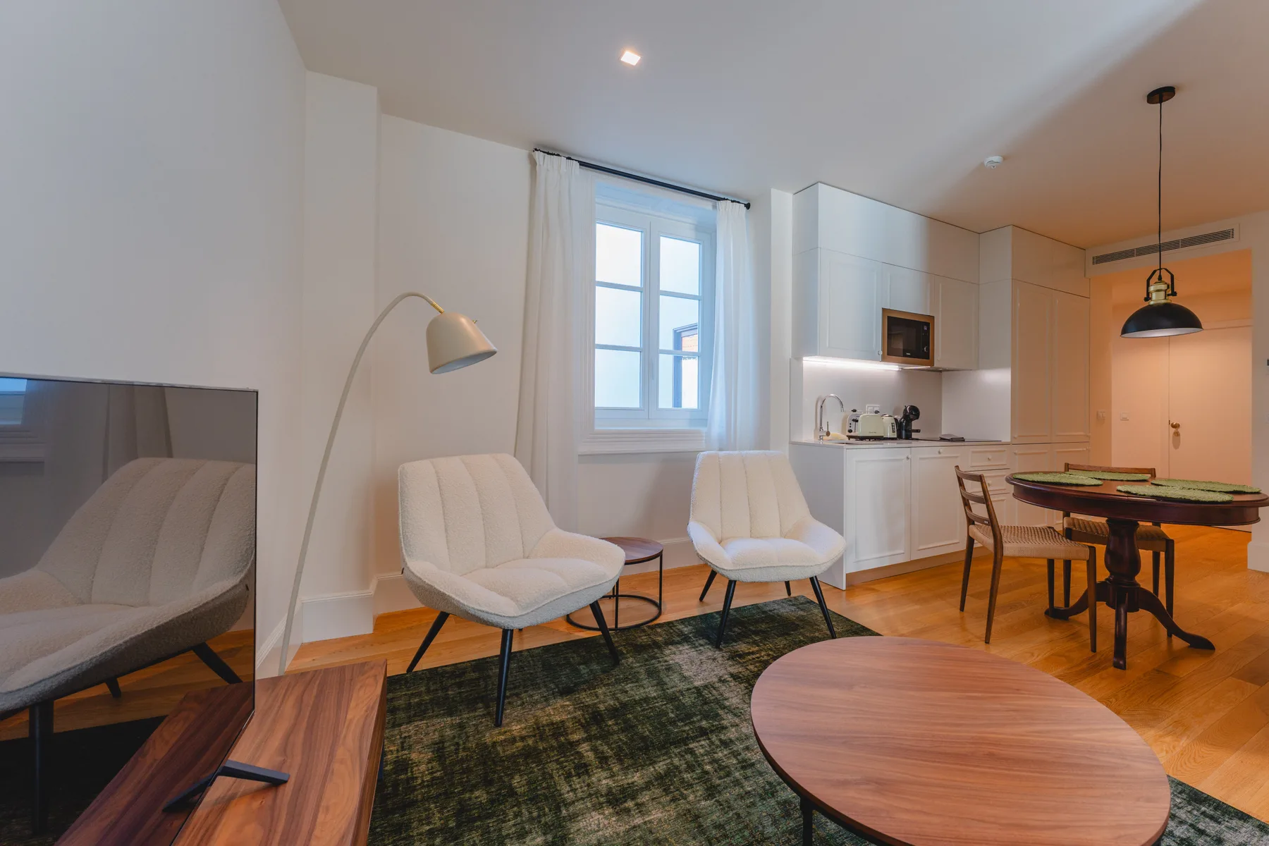 Sala de estar con asientos, un televisor y una mesa de comedor.