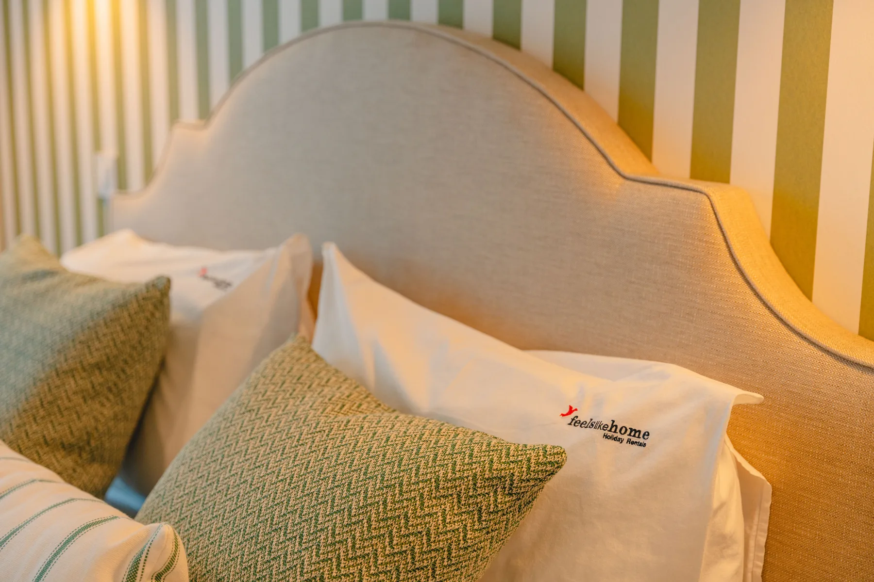 Un dormitorio con una cama vestida con ropa blanca y cojines estampados.