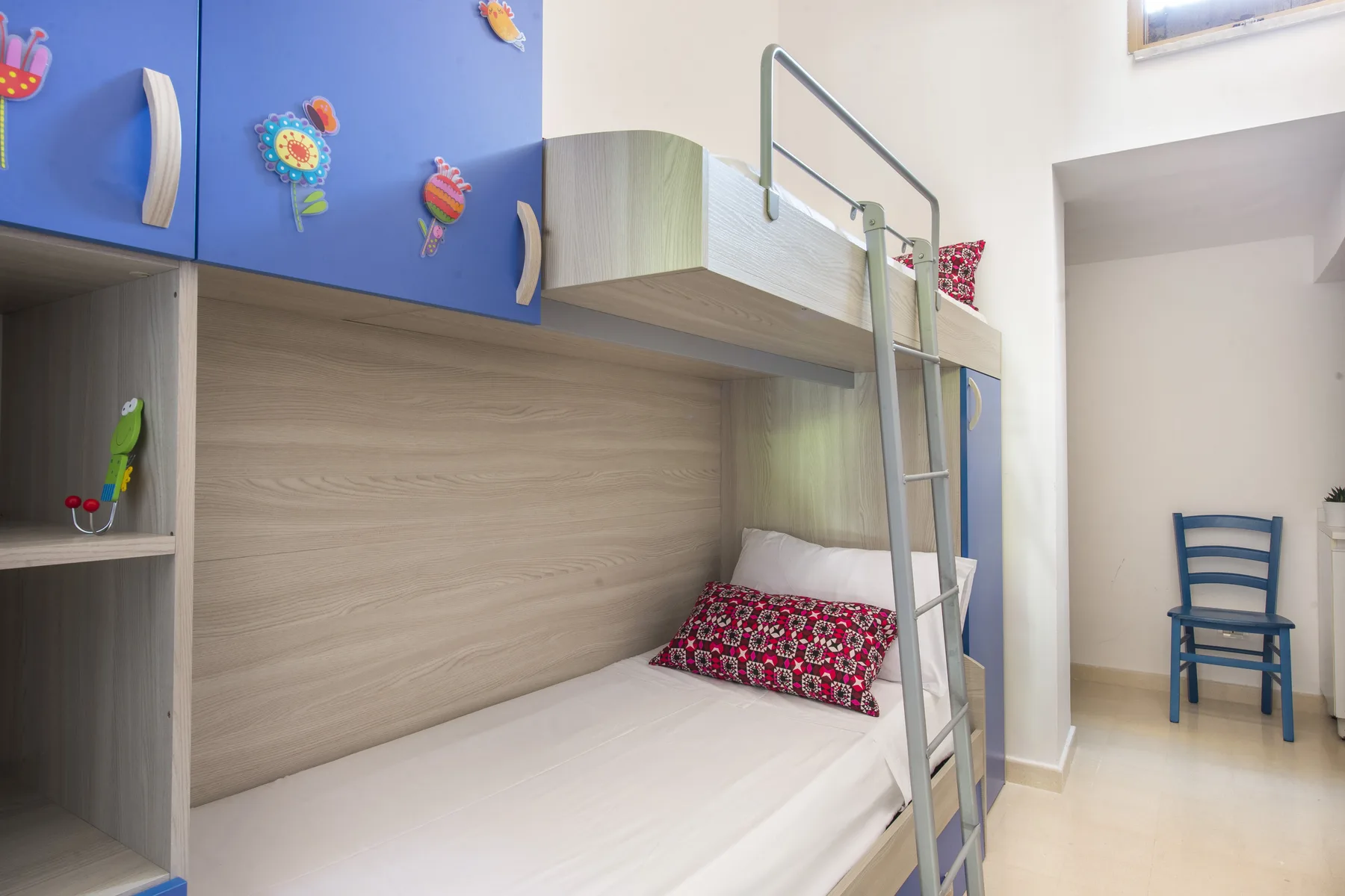 Un dormitorio infantil con una litera y una silla azul.