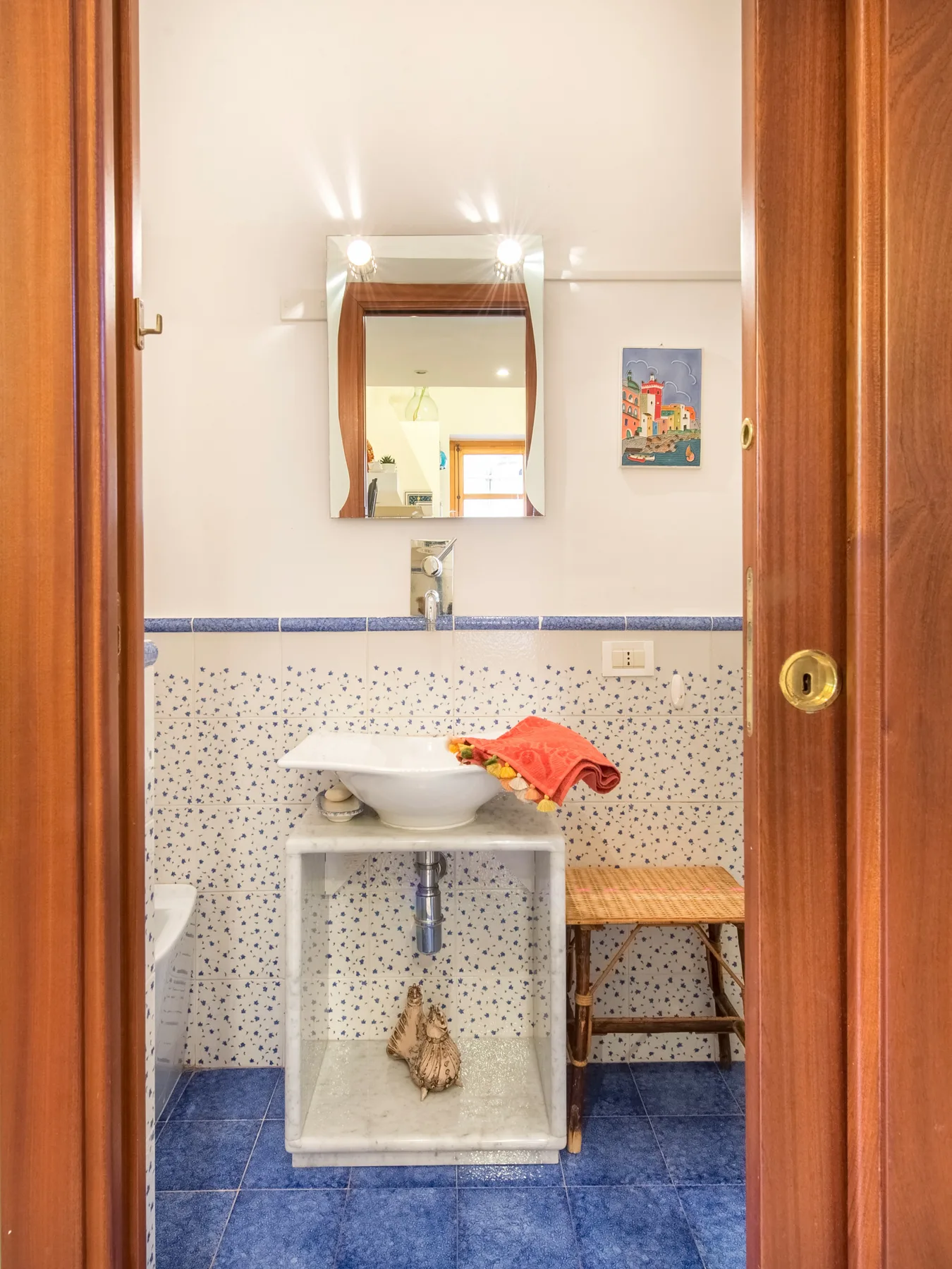 Un baño con lavabo, espejo y suelo de baldosas azules.
