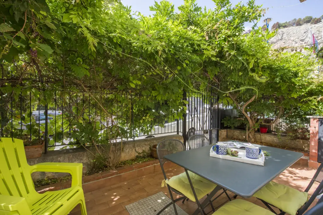 Una zona de comedor al aire libre con una mesa bajo enredaderas frondosas.