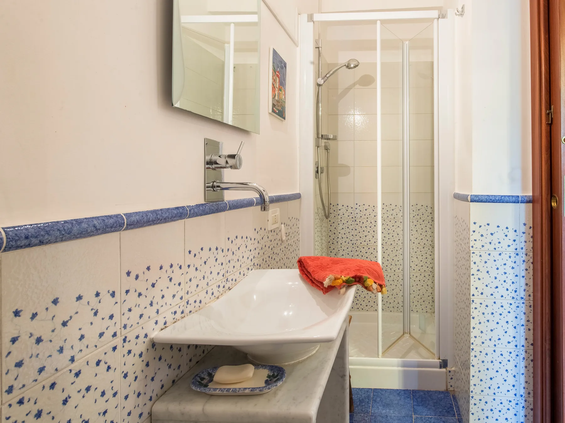 Un baño con lavabo y una ducha con mampara de vidrio.