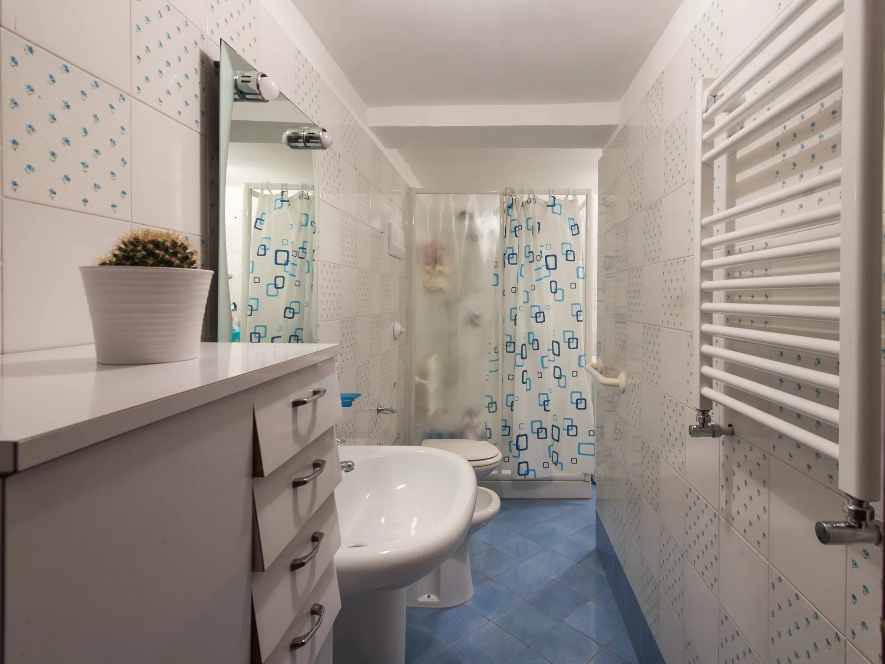 Un baño con lavabo, inodoro y cortina de ducha con motivos azules.