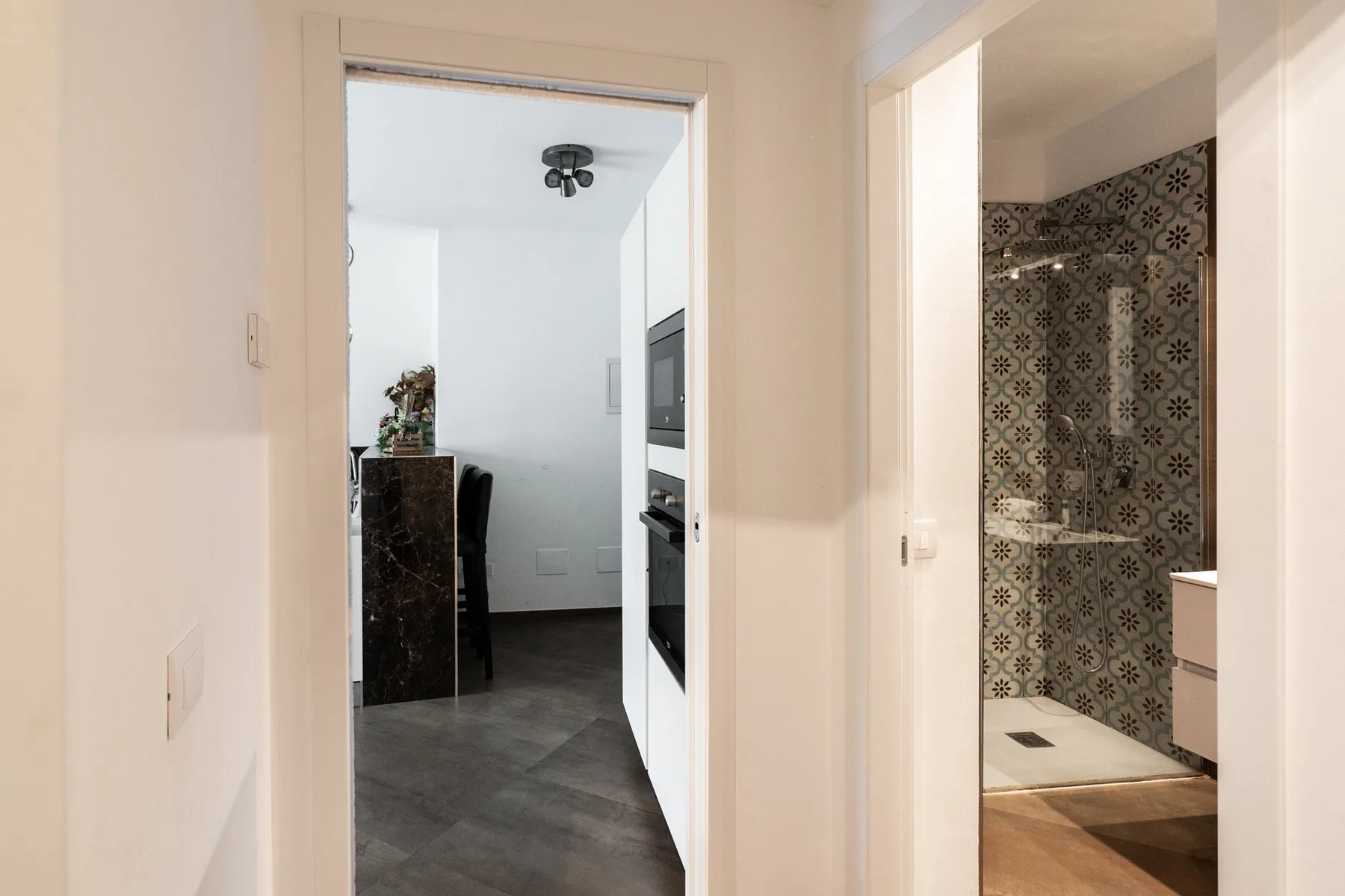 A hallway opens onto a kitchen and a bathroom with patterned tile.