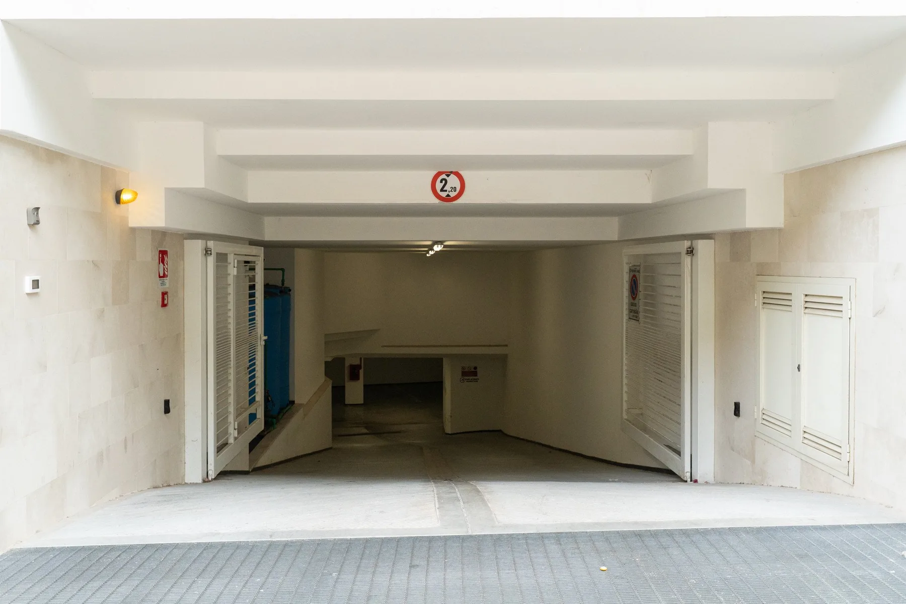A covered parking garage entrance opens onto a dim interior parking area.