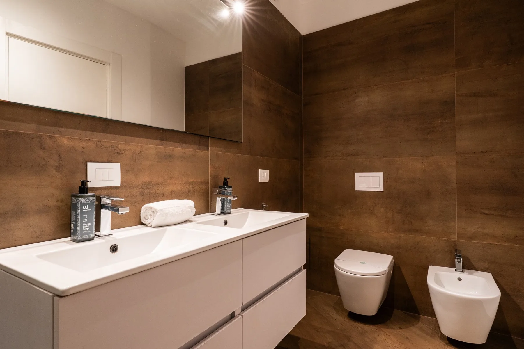 A bathroom with a long vanity, two sinks, and a toilet.