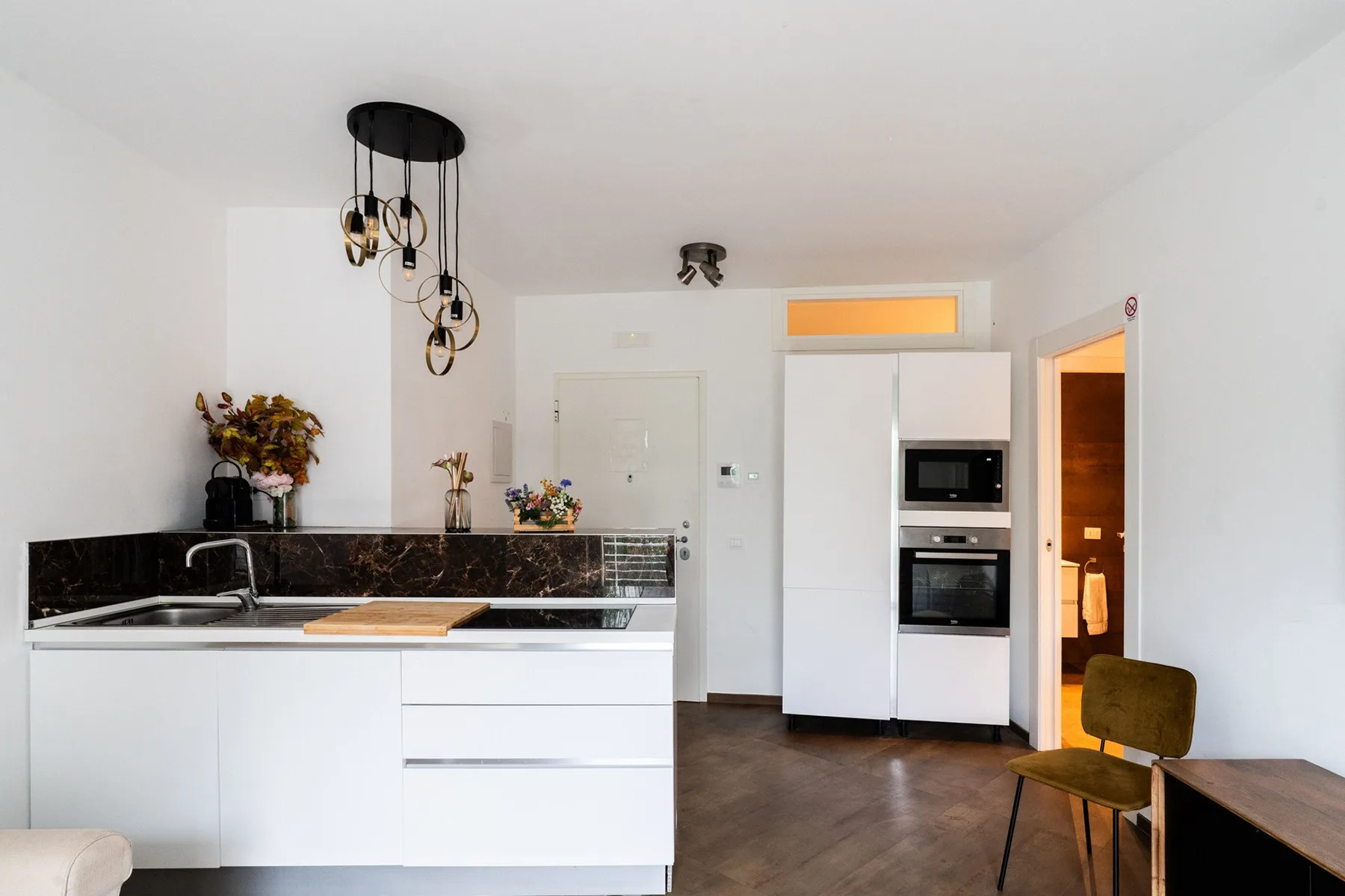 A bright kitchen with white cabinets, a dark countertop, and built-in appliances.