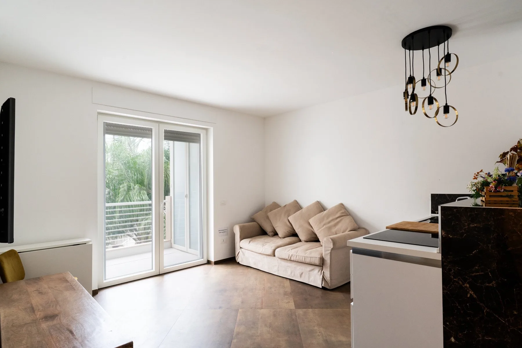 A bright living area with seating beside glass doors opening to a balcony.