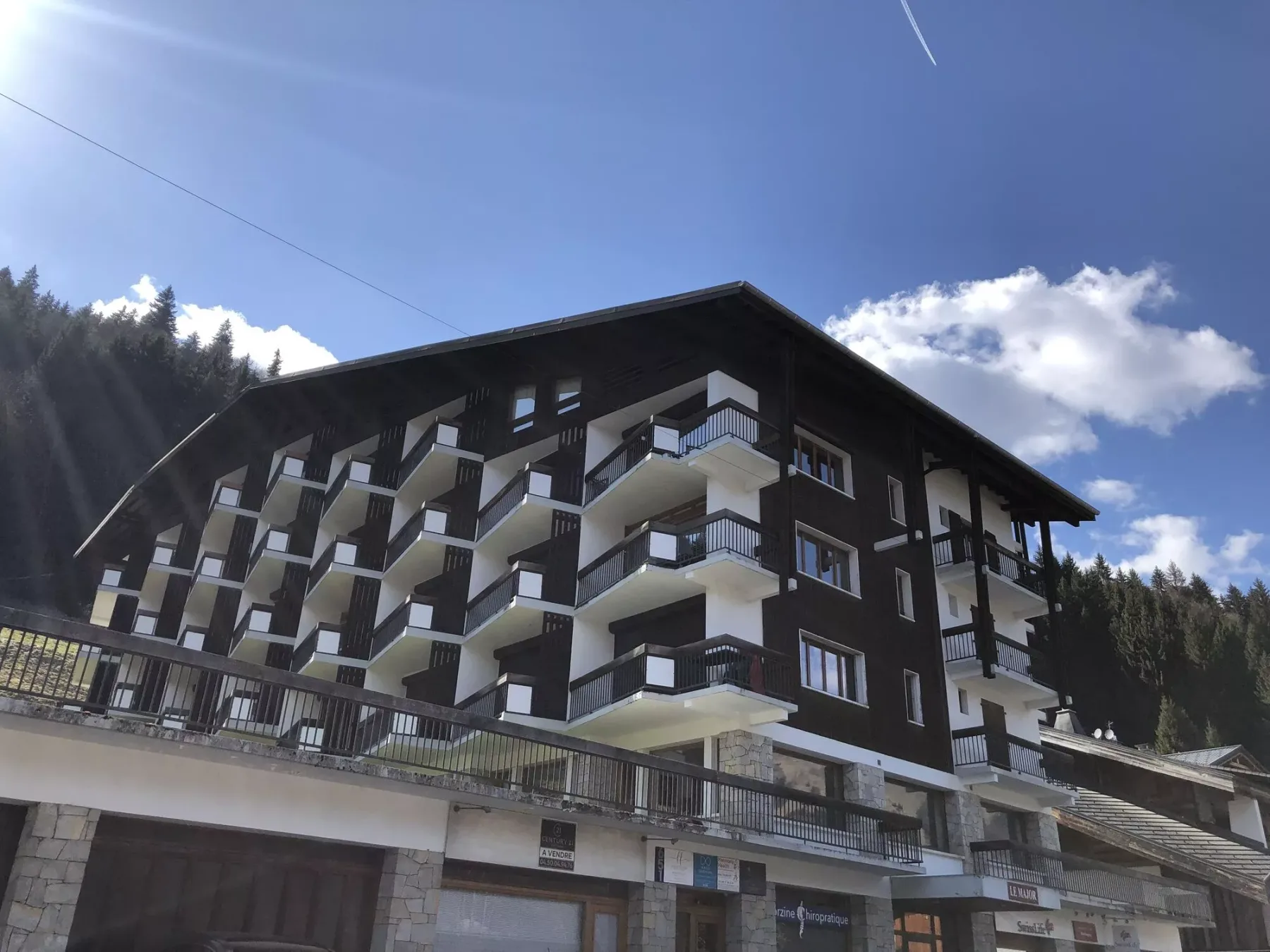Un edificio oscuro de varias plantas con filas de balcones se alza bajo un cielo despejado.