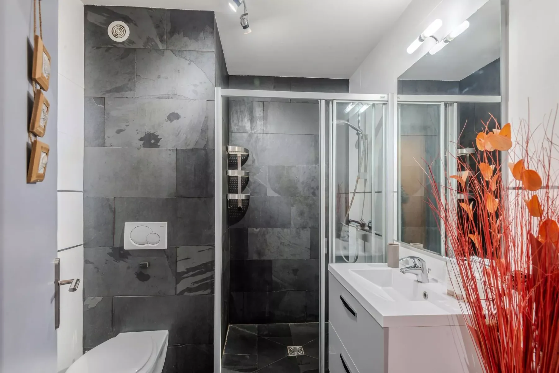 Un baño moderno con una ducha de vidrio y un lavabo blanco.