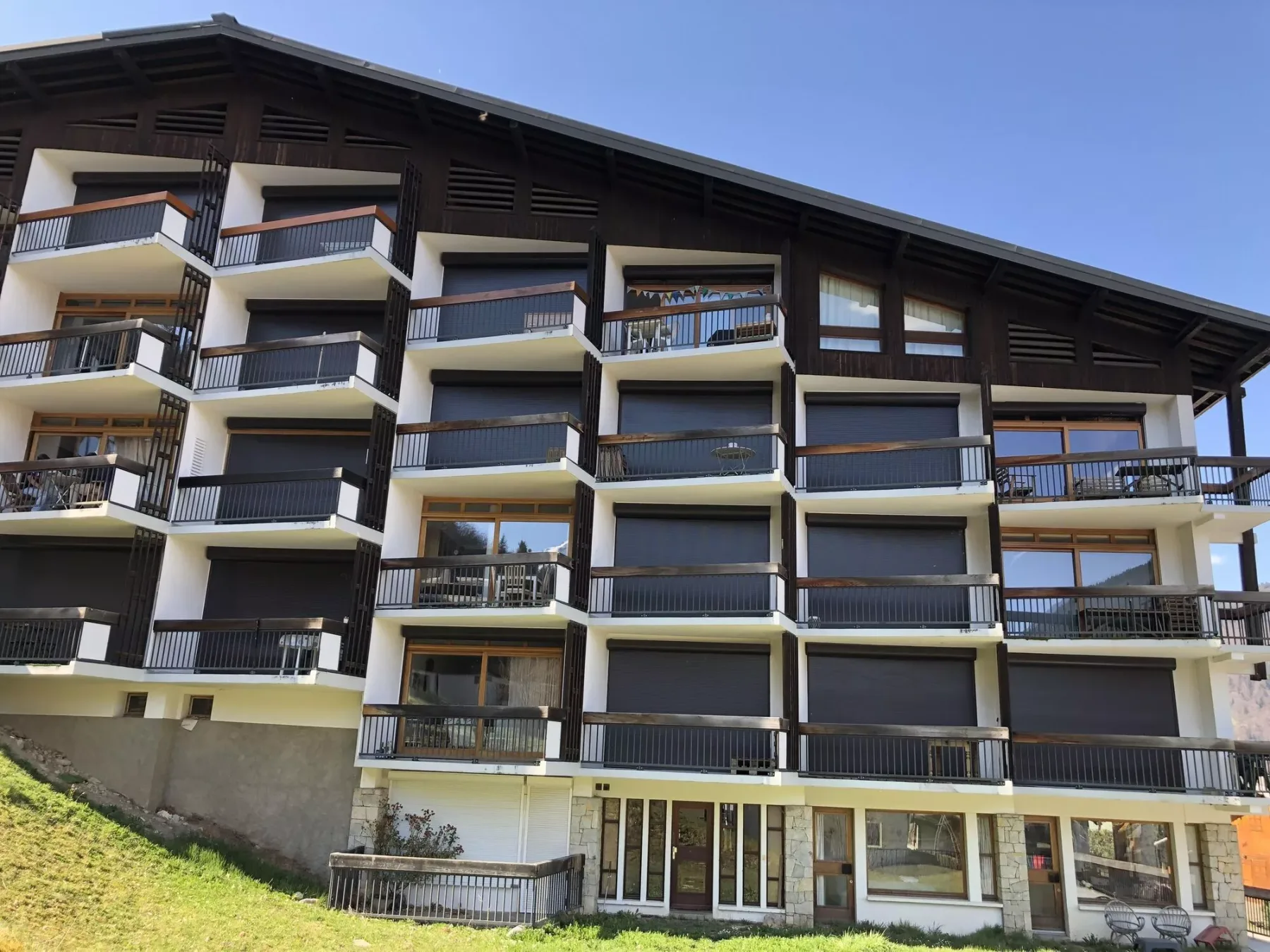Un edificio de varias plantas con filas de balcones bajo un amplio tejado inclinado.