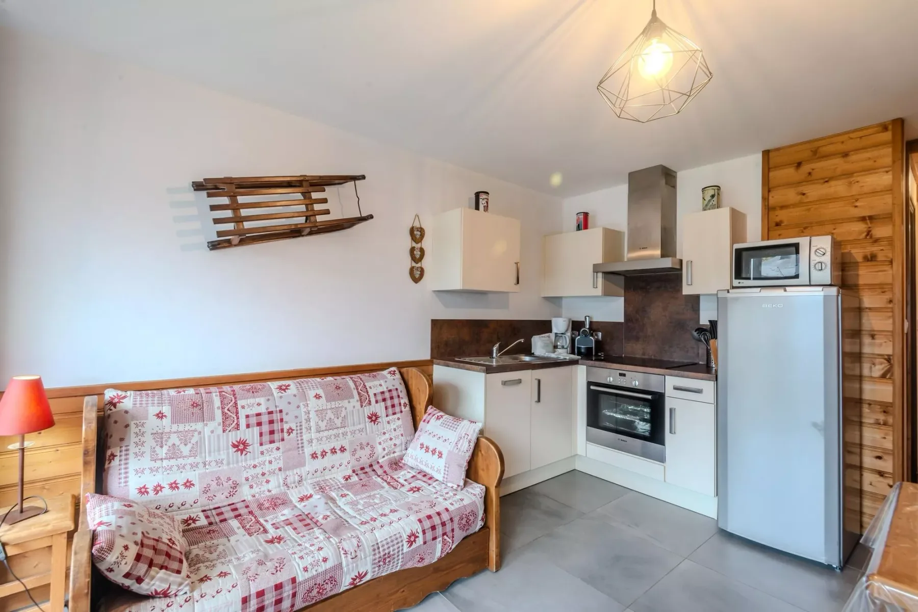 A compact living area with patterned seating beside a small kitchen.