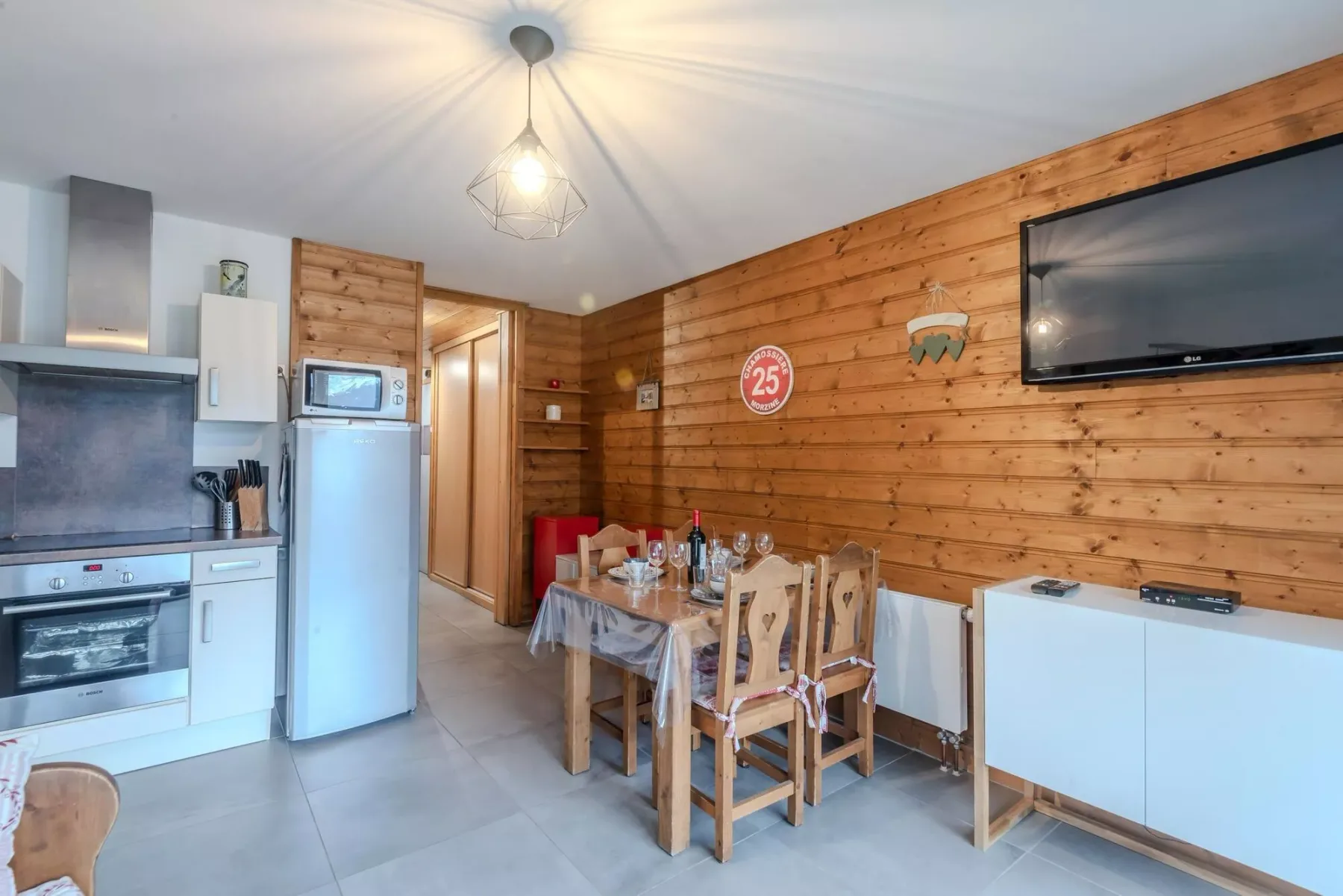 Una cocina compacta y comedor con paredes de madera y una mesa preparada para comer.
