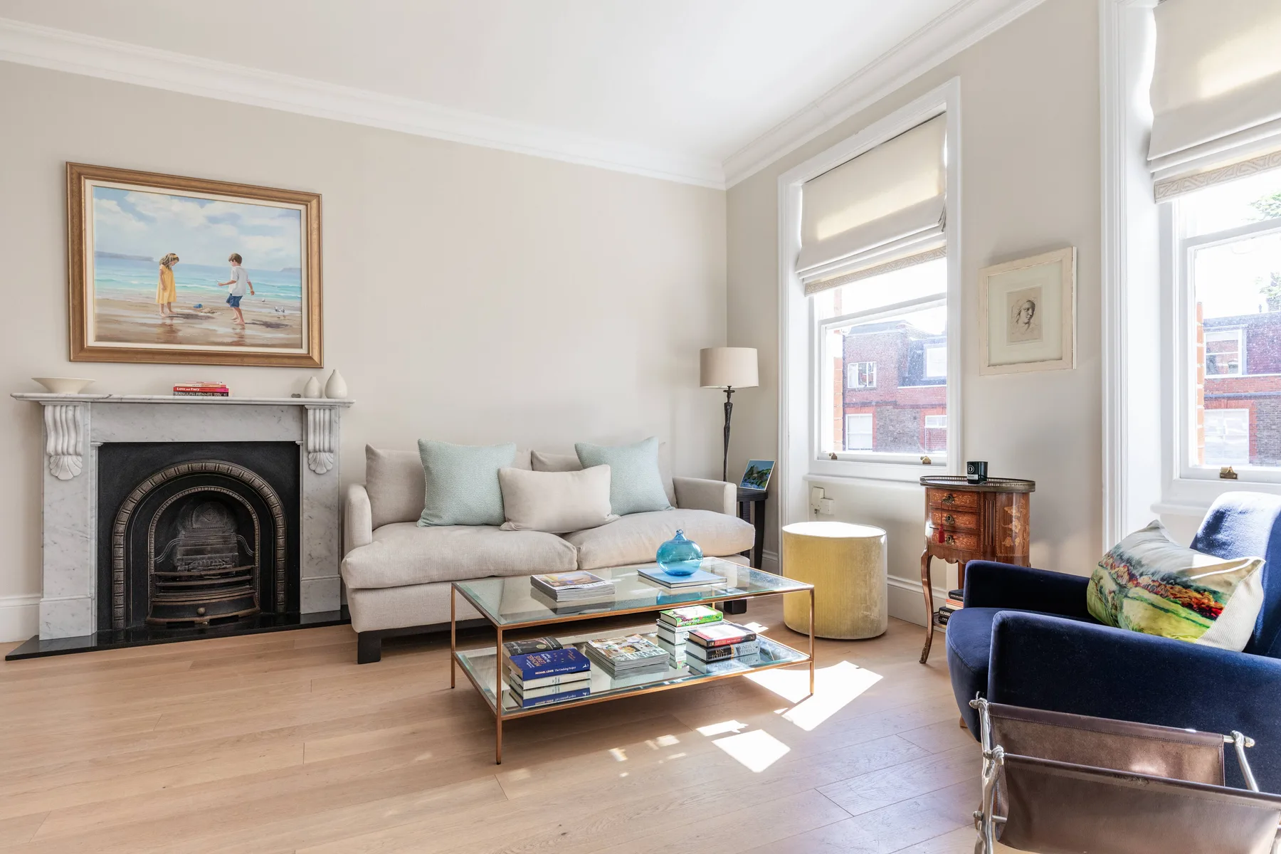 A bright living room with a fireplace, seating, and a glass coffee table.