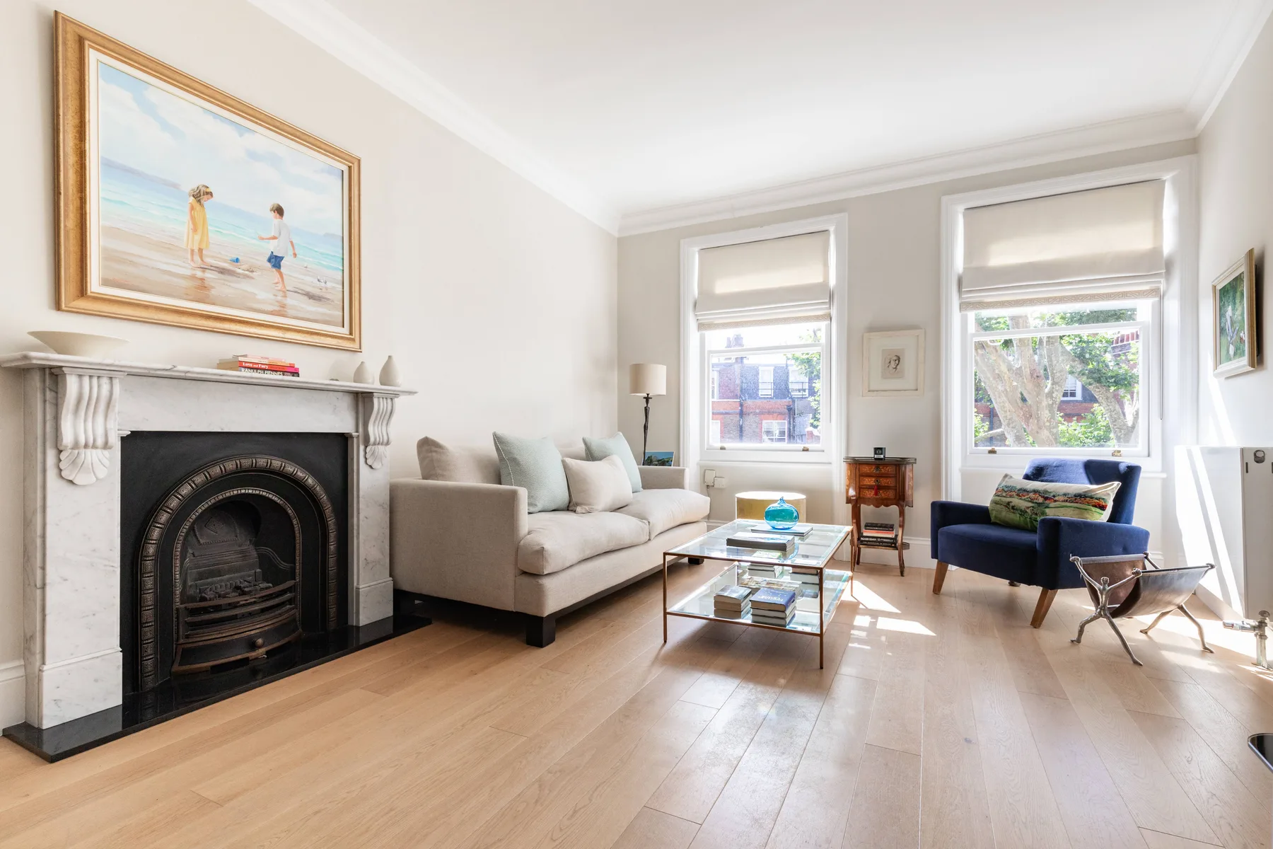 A bright living room with a fireplace, light seating, and windows.