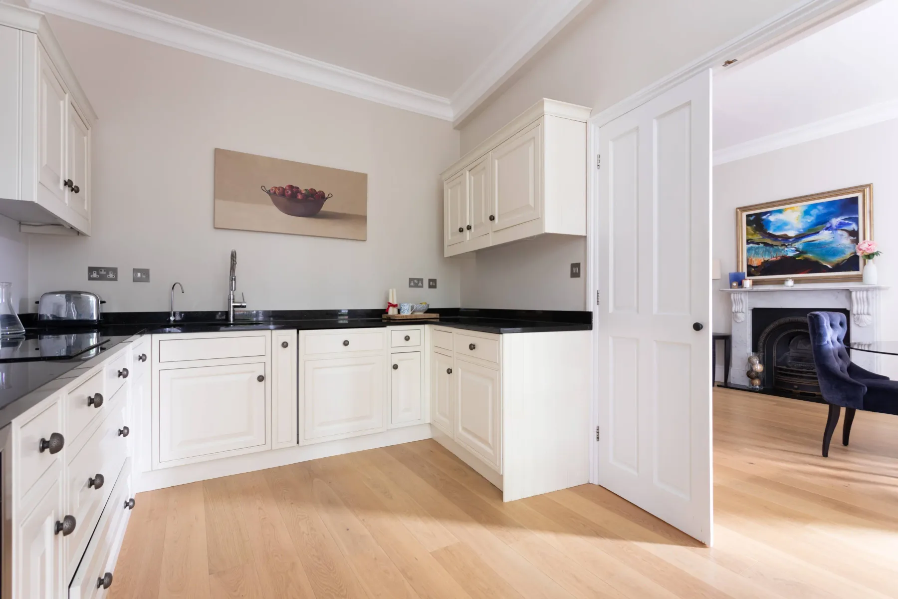 A bright kitchen with white cabinets and dark countertops.