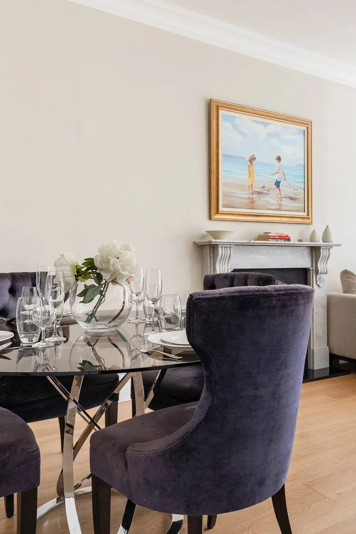 A dining area with a glass table, upholstered seating, and a fireplace.