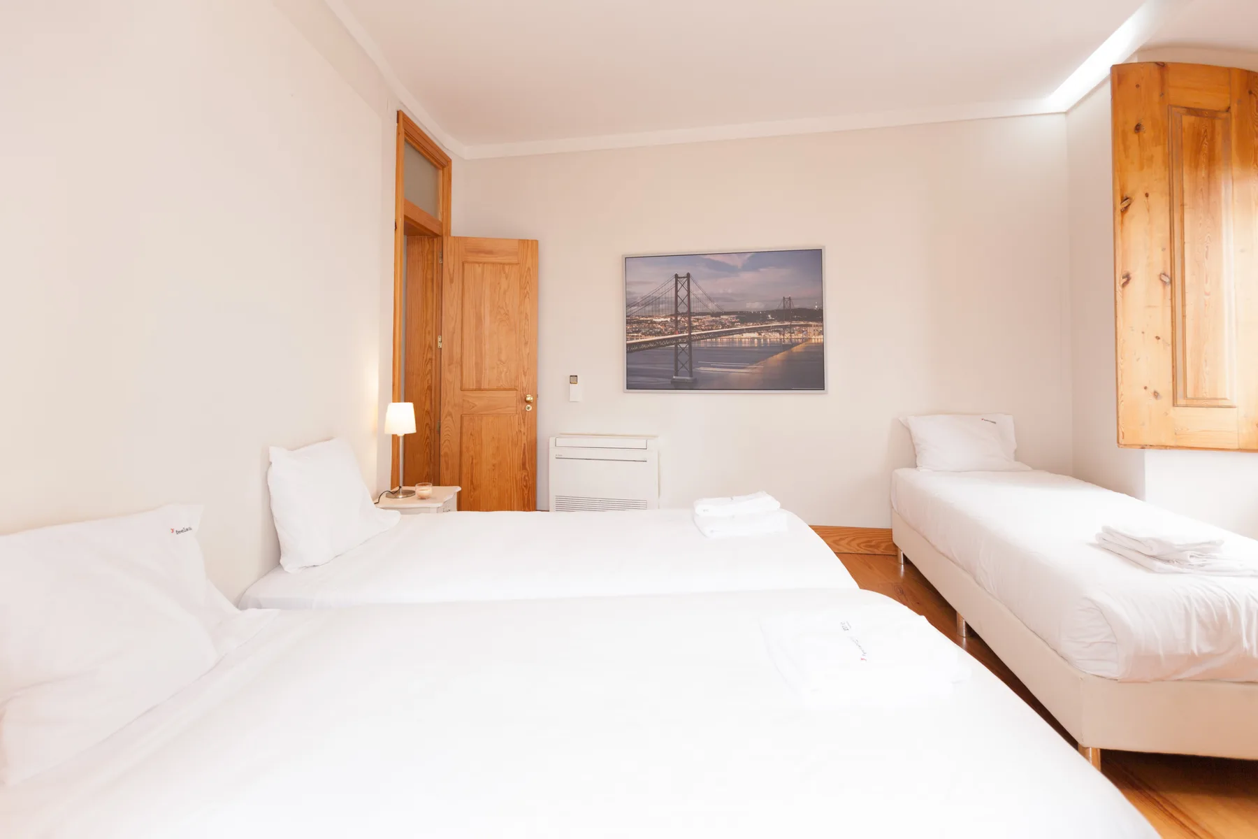 Dormitorio con varias camas, ropa de cama blanca y un cuadro en la pared.