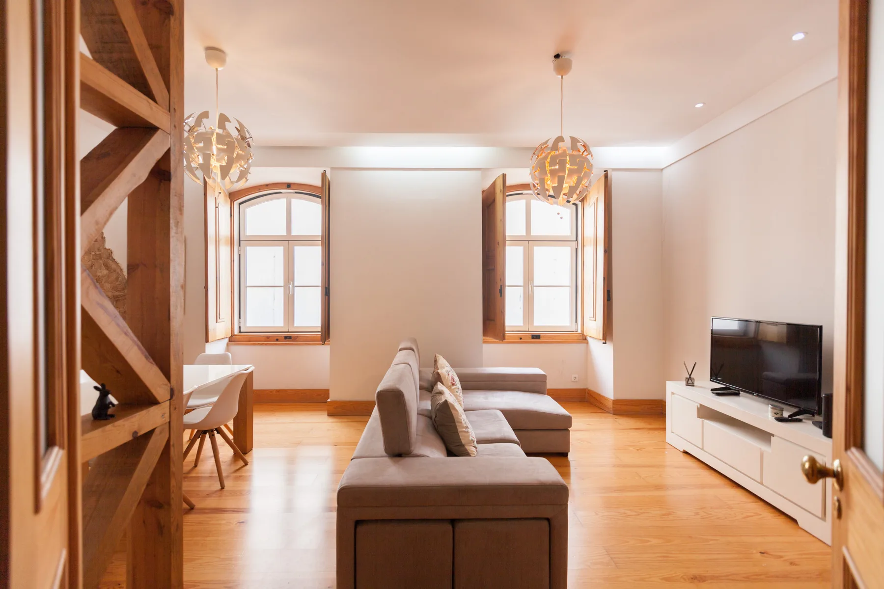 Una sala luminosa con asientos, dos ventanas y un televisor.