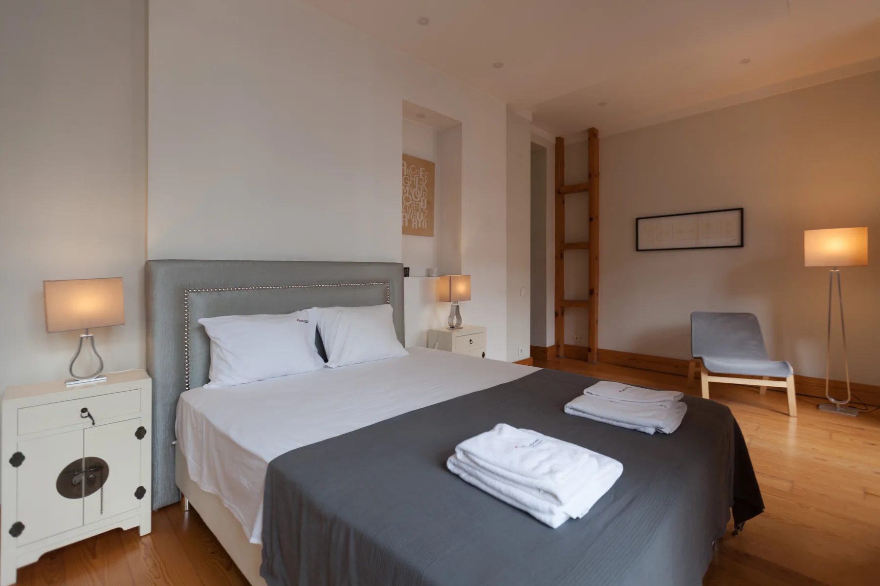 Un dormitorio con una cama bien hecha y mesitas de noche.
