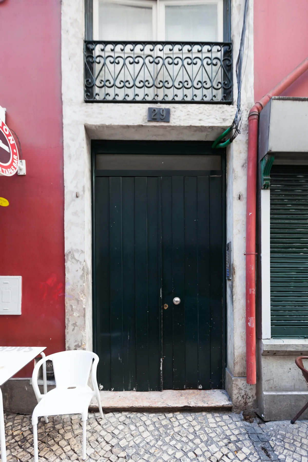 Una puerta de entrada oscura está bajo un pequeño balcón en un edificio rojo.
