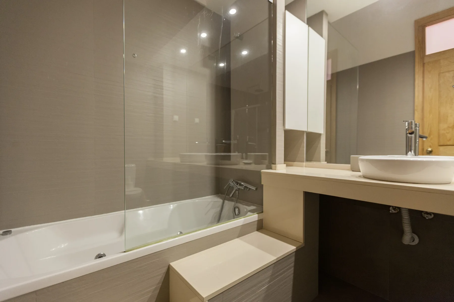 Un baño con bañera, mampara de vidrio y lavabo.