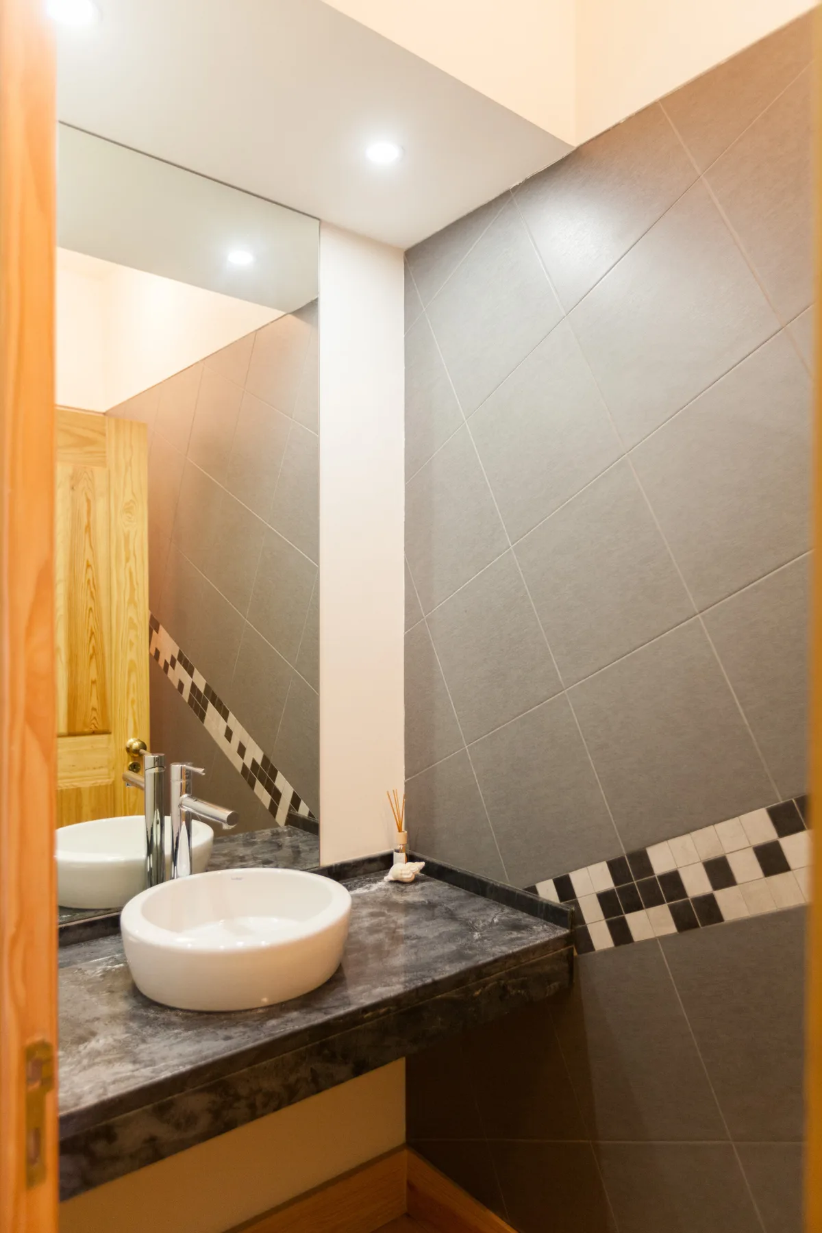 Un lavabo de baño con un espejo y paredes revestidas de azulejos.